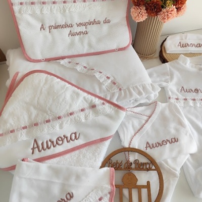 Conjunto branco de roupa e acessórios bordados para bebé com nome Aurora e vaso com flores