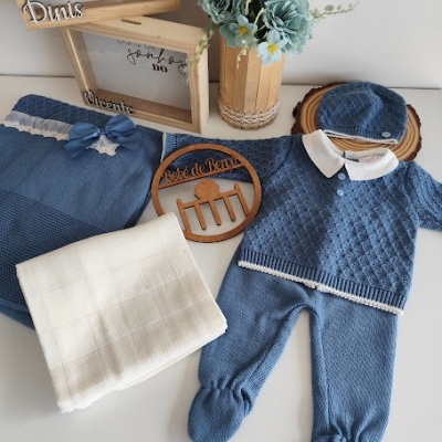 Conjunto roupa bebé azul, manta branca, caixas madeira, vaso flores decorativas