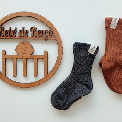 Dois pares de meias infantis com etiqueta PHIL, ao lado de placa decorativa Bebé de Berço de madeira