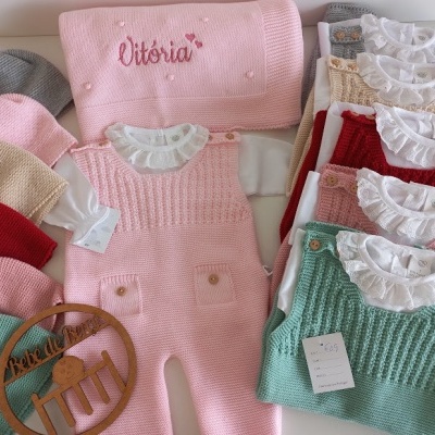 Conjunto de roupa de bebé em tricô colorida com manta bordada VITÓRIA e cabide de madeira.