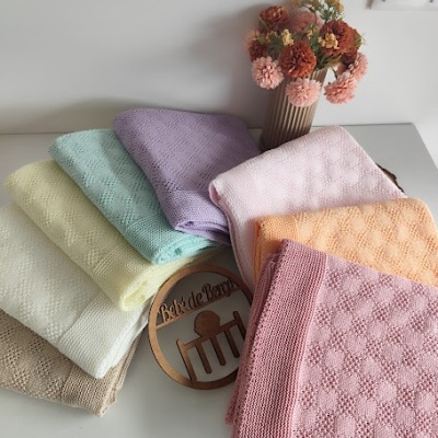 Toalhas coloridas empilhadas com padrões texturizados e um vaso com flores