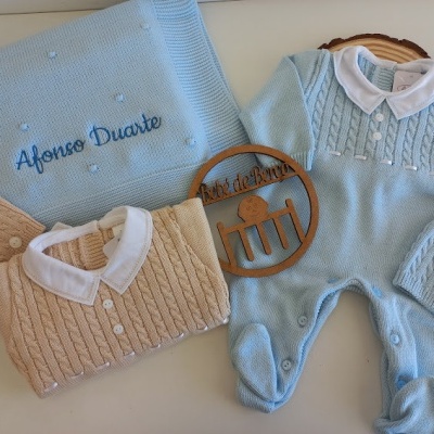 Conjunto de roupa e acessórios de bebé em malha azul e bege com manta bordada e decoração de madeira