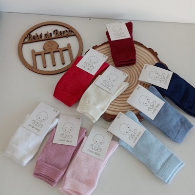 Oito pares de meias infantis coloridas em mesa branca com placa de madeira com texto