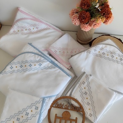 Toalhas de bebé brancas com bordados coloridos e vaso com flores artificiais