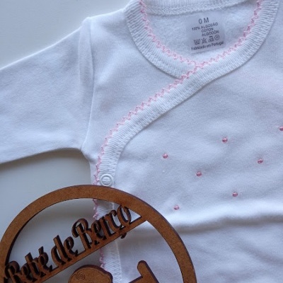 Body branco de bebé com bordados rosa e ornamento de madeira com texto