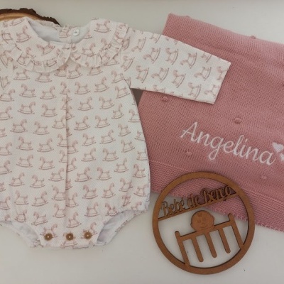 Body de bebé branco e rosa com padrão de cavalinho de pau, manta rosa com nome 'Angelina' bordado e círculo de madeira gravada