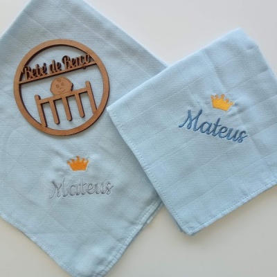 Dois panos de boca com nomes bordados e uma placa decorativa de madeira