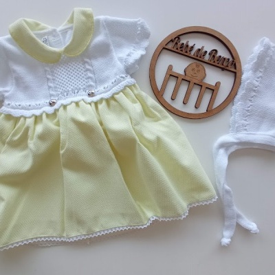 Vestido de bebé amarelo e branco, gorro branco e ornamento de madeira com texto