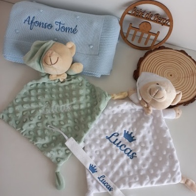 Mantas e panos de pelúcia com nomes bordados e chupeta personalizada sobre fundo branco