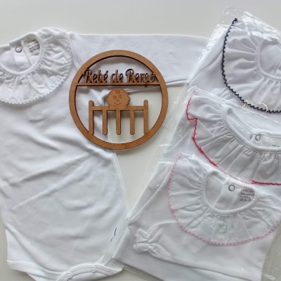 Body branco de bebé com gola bordada e bodies semelhantes embalados com placa de madeira gravada