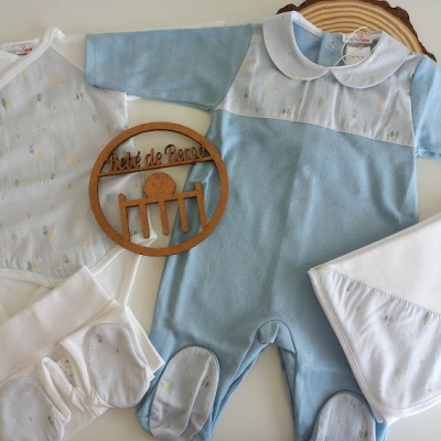 Conjunto de roupa de bebé branco e azul claro com sapatinhos e cobertor em fundo claro