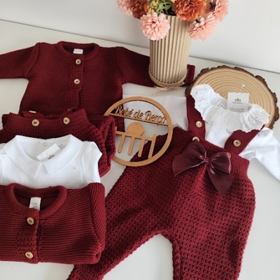 Roupa de bebé em malha vermelha e body branco com flores em vaso e placa de madeira