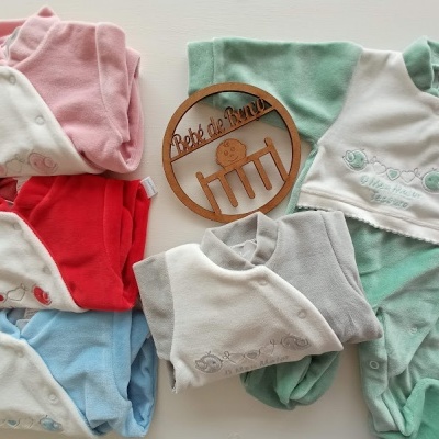 Conjunto de pijamas de bebé em várias cores com placa de madeira 'Bebé do Arraiá'