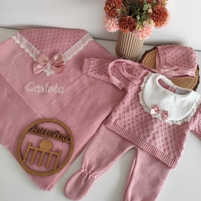 Conjunto de roupa de bebé rosa em malha com manta bordada, macacão, babete e chapéu, com vaso de flores