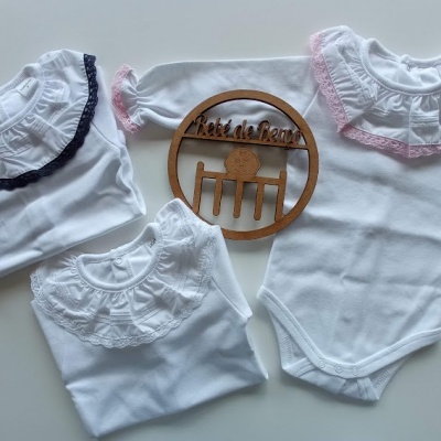 Três bodies brancos para bebé com gola rendada e decoração de madeira com texto