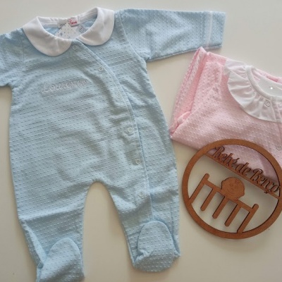 Conjunto de roupas de bebé azul e rosa com placa redonda de madeira