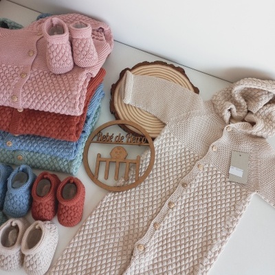 Roupas de bebé em tricot com padrão texturizado e várias cores com sapatinhos correspondentes.