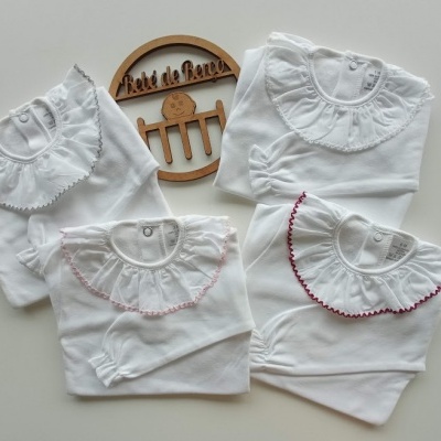 Bodies brancos para bebé com golas bordadas e placa de madeira com texto