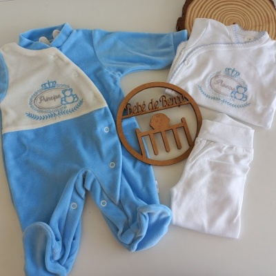 Conjunto de roupa de bebé azul e branco com bordados e elemento decorativo em madeira