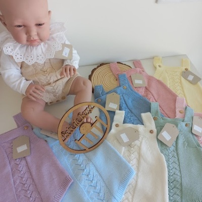 Boneco bebé com fatos de malha coloridos e um cesto de palha