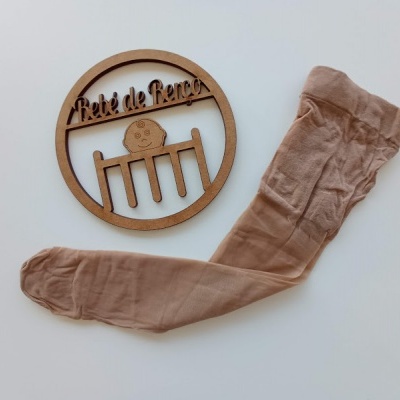 Meia-calça bege clara e placa decorativa de madeira com texto 'Petite de Paris'