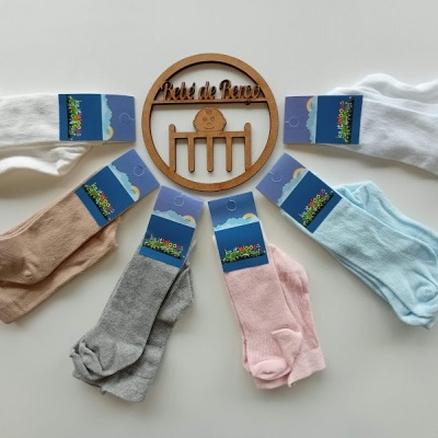 Seis pares de meias coloridas com etiquetas azuis dispostos em semicírculo junto a objeto de madeira redondo