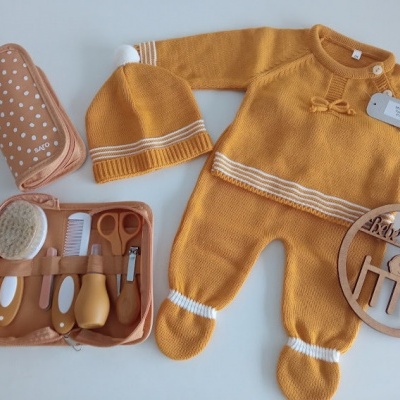 Conjunto de roupa e acessórios de bebé, macacão amarelo, gorro, necessaire com utensílios e placa de madeira
