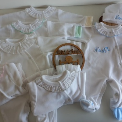 Conjunto de roupa de bebé branco com detalhes em azul, verde, rosa e bege e bordado com o nome Noah.