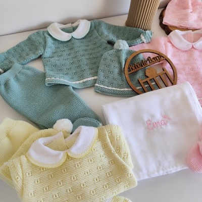 Conjunto de roupa de bebé em malha com diferentes peças coloridas e fralda bordada