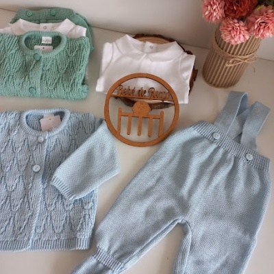 Conjunto de roupa de bebé em malha azul e verde com decoração de flores e ornamento de madeira