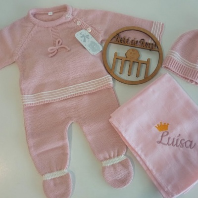 Conjunto de roupa de bebé rosa com macacão, gorro, manta bordada e enfeite de madeira