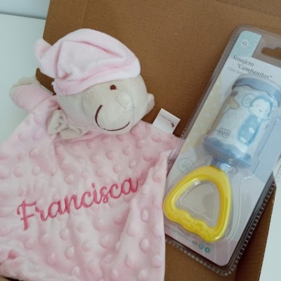 Brinquedo de pelúcia rosa bordado e chupeta em embalagem junto num fundo de cartão