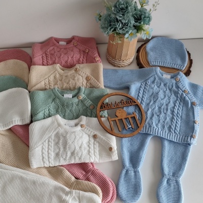 Conjunto de roupa de bebê tricotada em várias cores com botões de madeira, gorros e decoração com flores