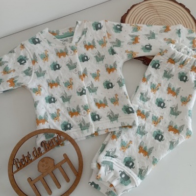 Pijama de bebé branco com padrão de animais e objeto redondo de madeira com inscrição