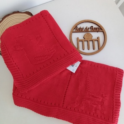 Cachecol vermelho de malha com padrão de animal em relevo e objeto de madeira com texto Pérolas de Banho