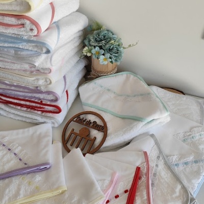 Jogo de toalhas brancas com bordados coloridos e arranjo de flores em vaso de madeira