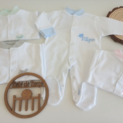 Quatro macacões brancos para bebé com detalhes coloridos e placa de madeira redonda