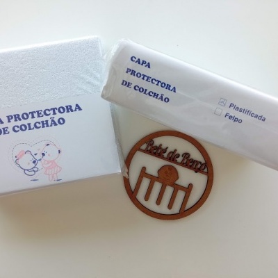 Capa protetora de colchão branca com embalagem e desenhos de crianças, texto azul