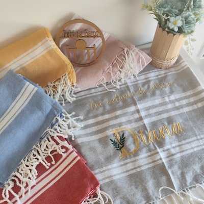 Lenços coloridos com franjas e lenço cinzento bordado com nome Diana com decoração de planta e sinal de madeira.