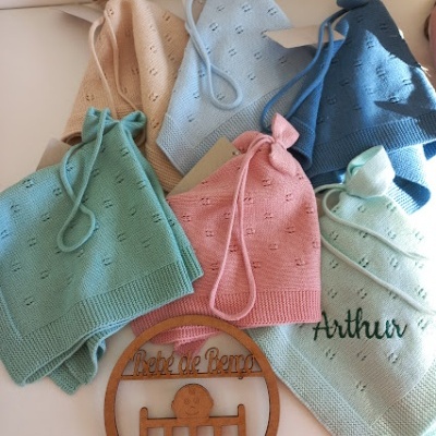 Toucas de malha coloridas em tons pastel com placa decorativa de madeira.