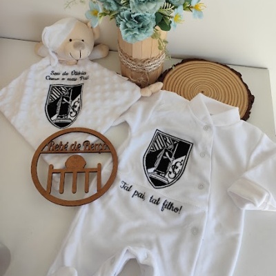 Conjunto de bebé branco com emblema e texto bordado, arranjo floral e ornamento de madeira