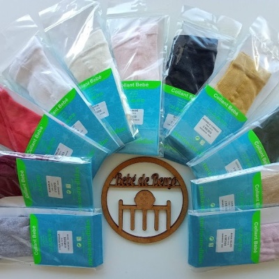 Meias para bebé em várias cores embaladas individualmente com etiquetas verdes, dispostas em círculo com emblema de madeira no centro.