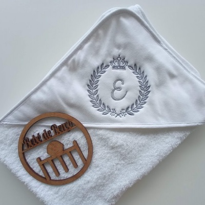 Toalha branca com bordado cinza e objeto redondo de madeira