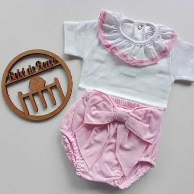 Conjunto de bebé branco e rosa com folho e laço, sobre fundo branco