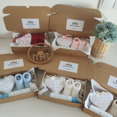 Caixas de cartão abertas com roupas de bebé coloridas e acessórios, decoração floral em fundo claro