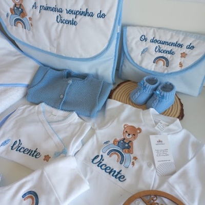 Conjunto de roupa de bebé azul e branca com bordados personalizados e acessórios organizadores.