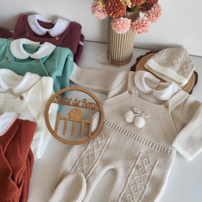 Conjunto de roupa de bebé tricotada com padrão em ponto fantasia e arranjo de flores secas em vaso de papel