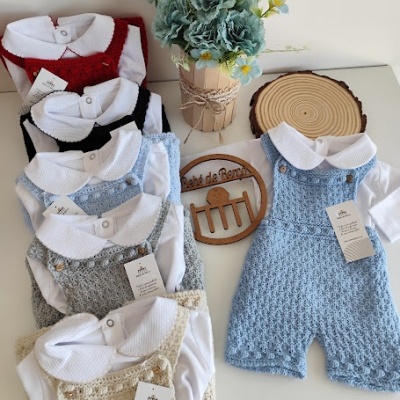 Conjuntos de roupa para bebé em várias cores com camisa branca e jardineira de malha, arranjo de flores azuis