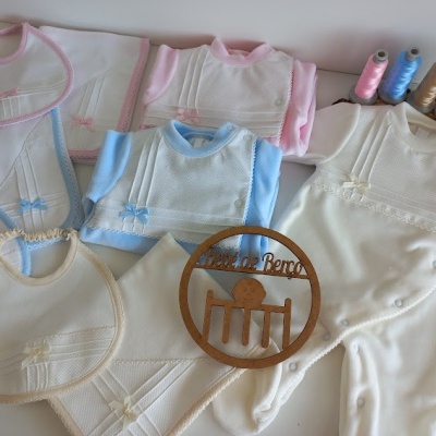 Produtos de bebé em tecido branco, azul, rosa e bege com rendas e laços