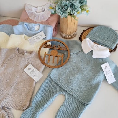 Roupas de bebé em várias cores com etiqueta e decoração de flores e madeira